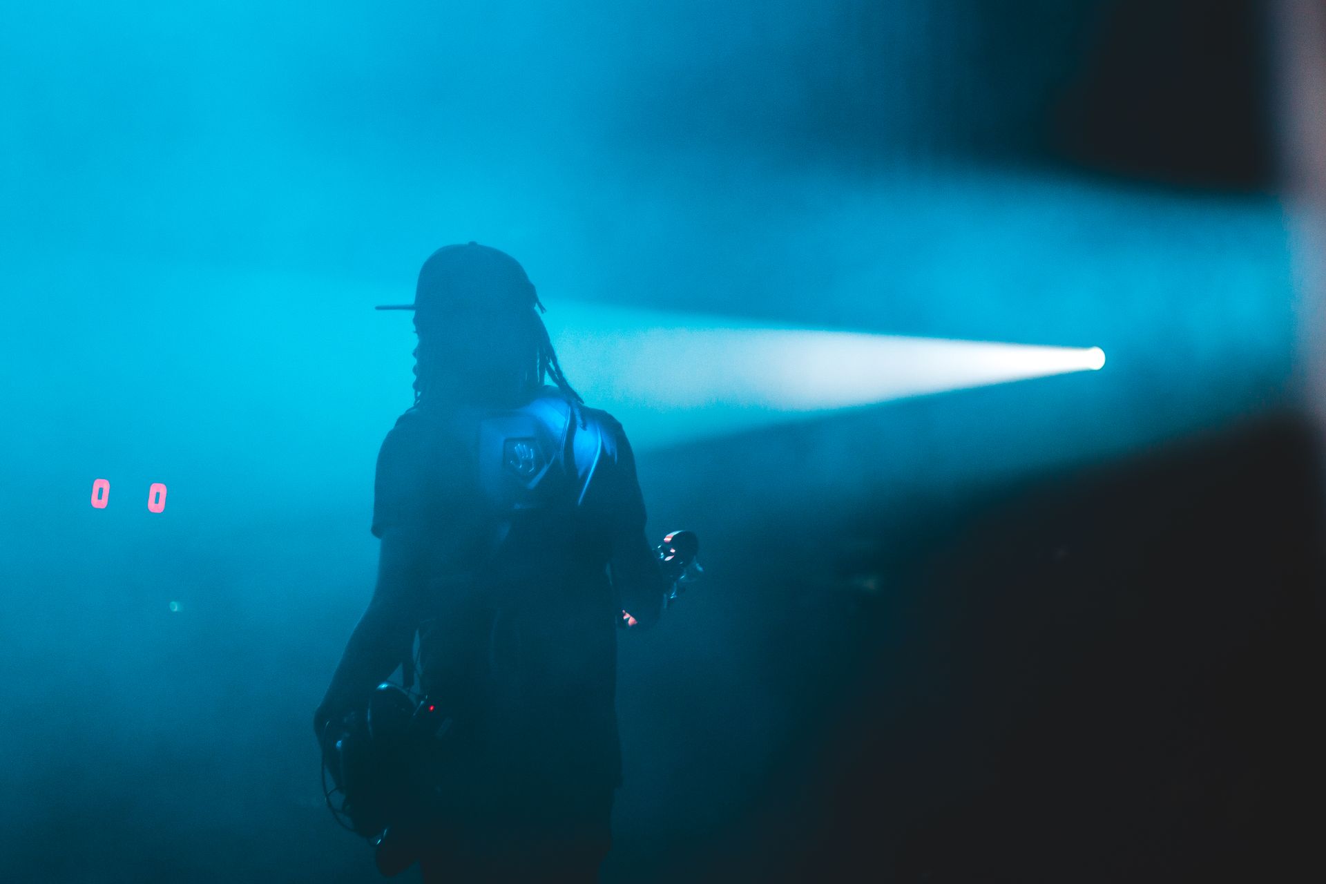 One figure on a dark stage, a single beam through fog